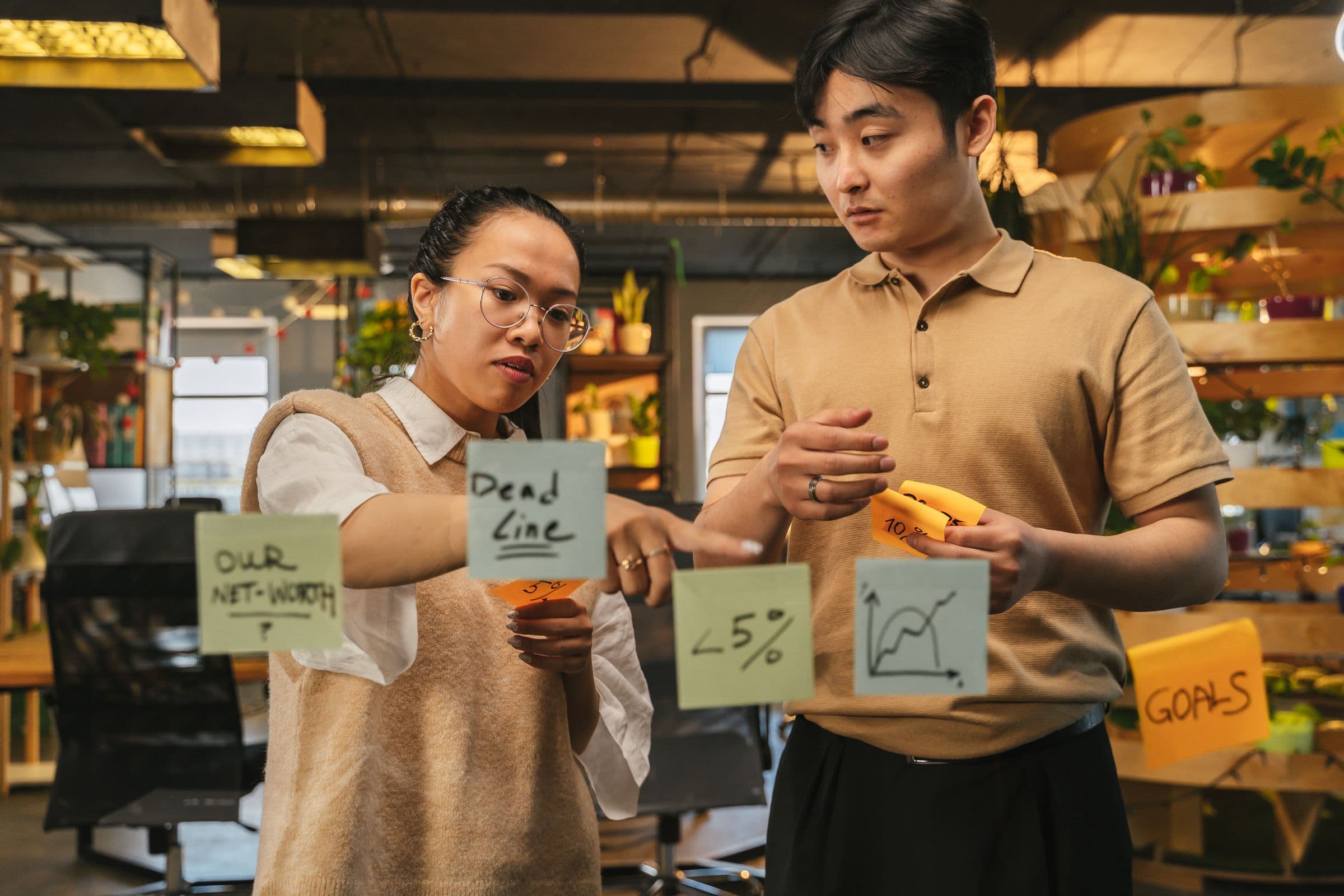 Two colleagues planning with sticky notes on a glass board